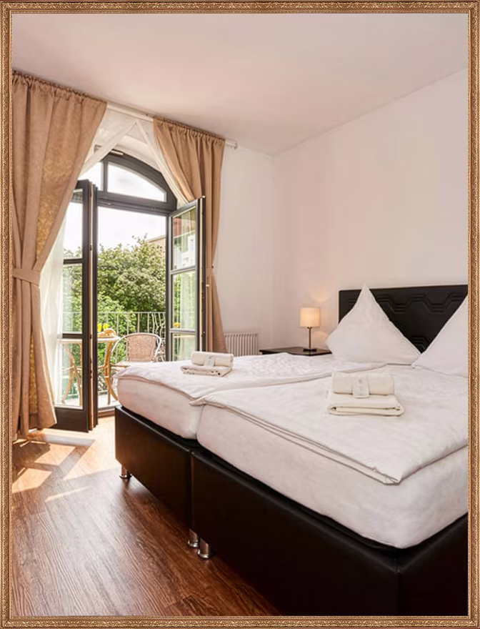 Bright hotel room at Matzbach with a double bed and balcony door onto the greenery in Berlin-Kreuzberg