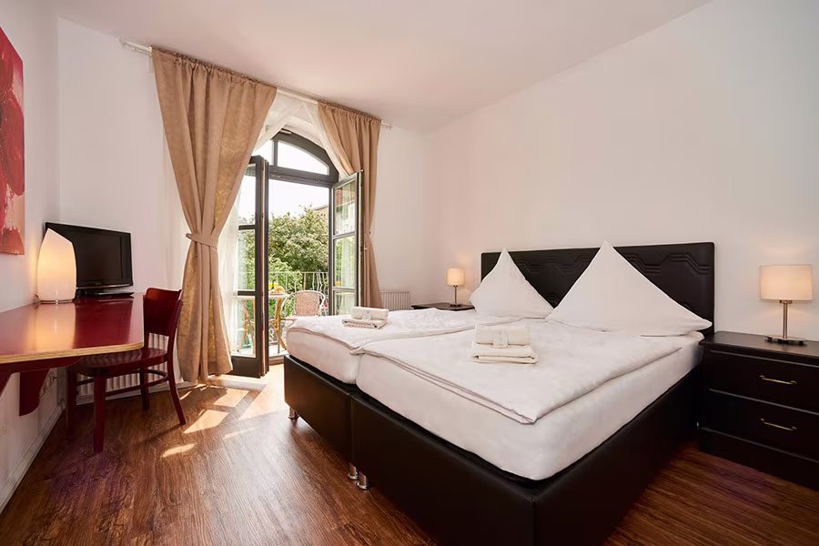 Family room at Hotel Matzbach with a double bed and balcony door to the leafy courtyard
